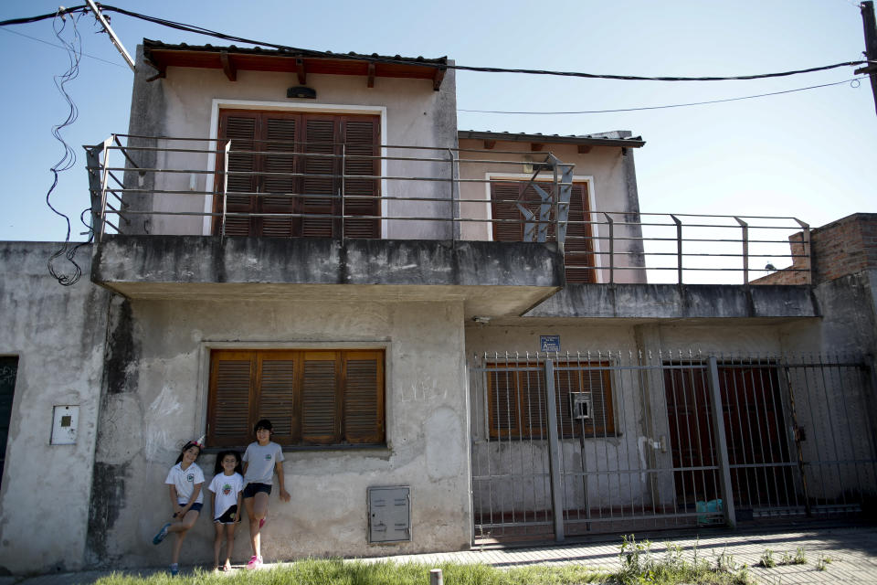 En la imagen del 5 de diciembre de 2019, niñas posan frente a la casa donde creció el astro argentino Lionel Messi en el modesto barrio La Bajada, en el sur de Rosario, su ciudad natal. (AP Foto/Natacha Pisarenko)