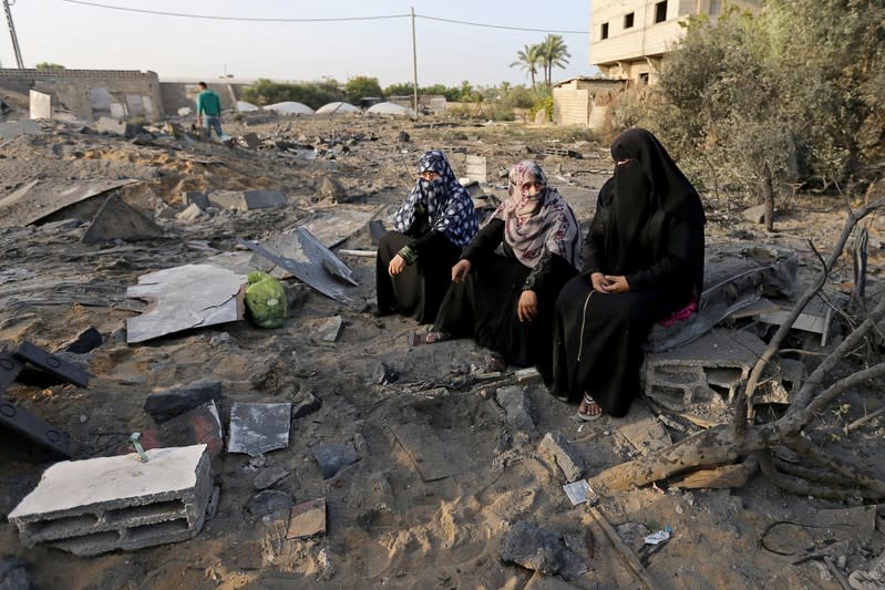 Palestinian women sit near the remains of a house destroyed in an Israeli air strike in the southern Gaza Strip