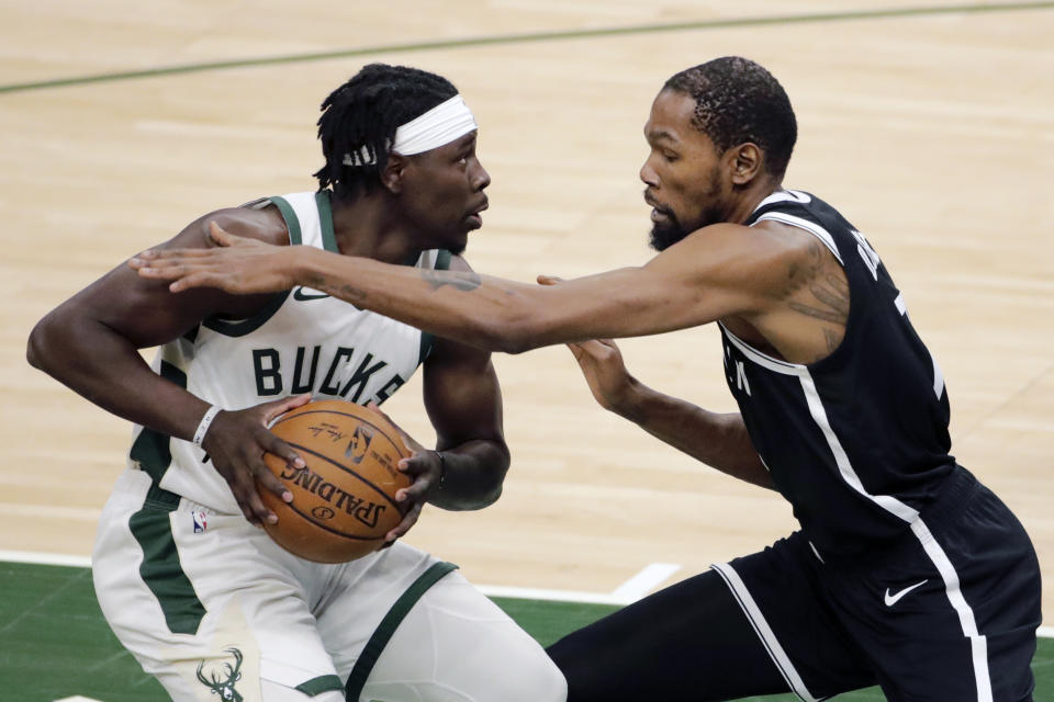 Milwaukee Bucks' Jrue Holiday, left, drives to the basket against Brooklyn Nets' Kevin Durant during the first half of an NBA basketball game Tuesday, May 4, 2021, in Milwaukee. (AP Photo/Aaron Gash)