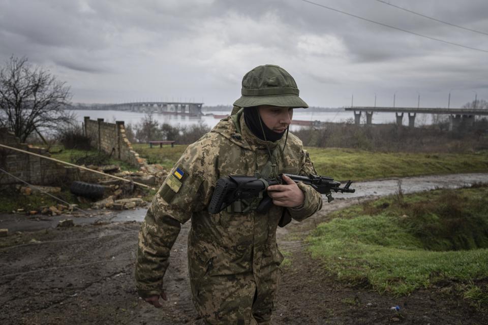 FILE - A Ukrainian serviceman patrols area near the Antonovsky Bridge which was destroyed by Russian forces after withdrawing from Kherson, Ukraine, Thursday, Dec. 8, 2022. With the war in Ukraine grinding through its 10th month, both sides are locked in a stalemated battle of attrition, which could set the stage for a new round of escalation. (AP Photo/Evgeniy Maloletka, File)