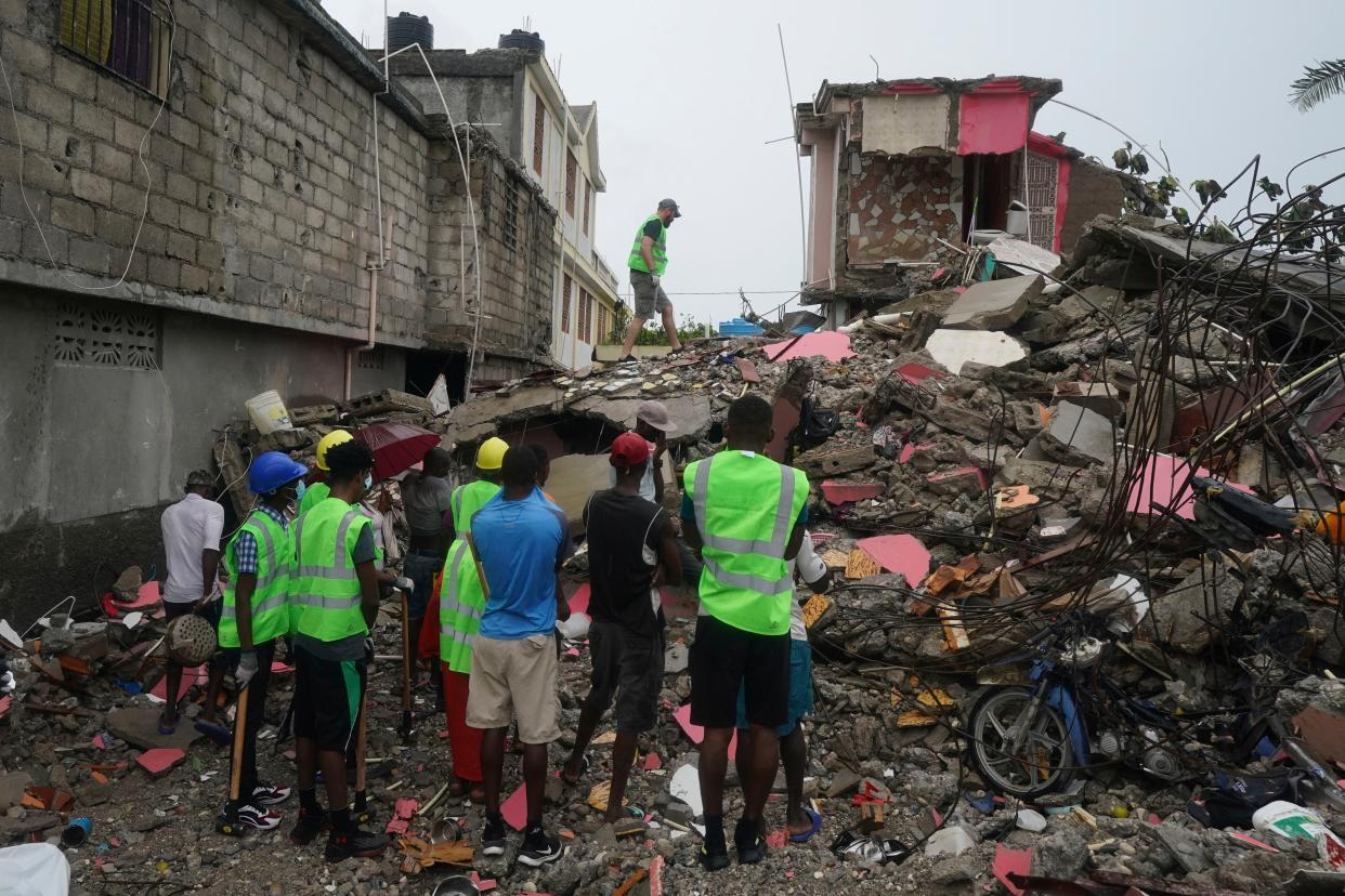 Canadian volunteer Randy Lodder walks over debris as he helps search for people who may be trapped under the earthquake rubble the morning after Tropical Storm Grace swept over Les Cayes, Haiti, Tuesday, Aug. 17, 2021, three days after the 7.2 magnitude quake.