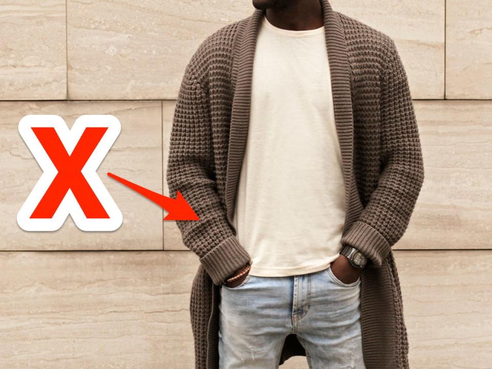 red x and arrow pointing at a long chunky cardigan someone is wearing