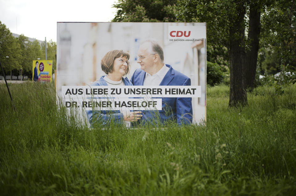 An election campaign poster from the Merkel's Christian Democratic Union, CDU, party stands near a road in the federal state Saxony-Anhalt's capital Magdeburg, Germany, Wednesday, June 2, 2021. The state vote on Sunday, June 6, 2021 is German politicians' last major test at the ballot box before the national election in September that will determine who succeeds Chancellor Angela Merkel. The poster shows ruling CDU governor Reiner Haseloff with bis wife Gabriele Haseloff and the slogan: 'Out of love for our homeland'. (AP Photo/Markus Schreiber)