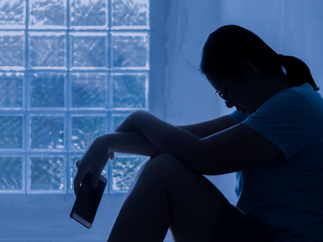 Silhouette Depress Woman Sitting And Hold Smartphone In Hand