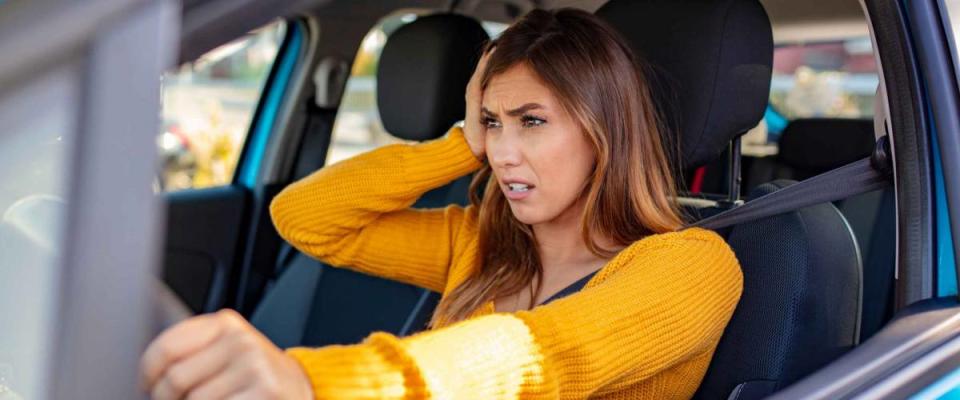 Nervous female driver sits at wheel, worried about paying too much for car insurance