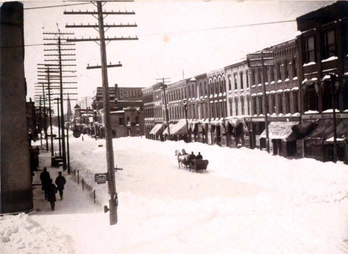 West Front Street in Monroe during the winter of 1900. The area was home to the Murphy House (proprietor, James Murphy, near Hurd and Sterling) and the U.S. Hotel (proprietor, Orry Adams). The steeple of St. Michael the Archangel Catholic Church can be viewed in the distance to the right. The church was founded on September 29, 1852, and construction of the current church building began in 1866. Prior to that time, the Harleston House sat on the property.