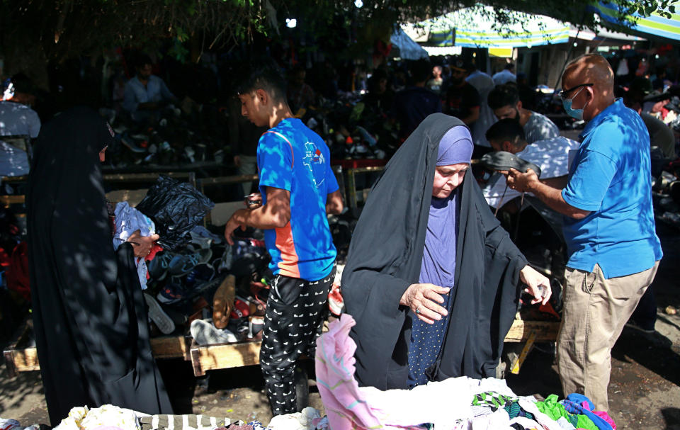 People shop for used clothes at the used-clothes market in Baghdad, Iraq, Tuesday, Oct. 20, 2020. Iraq is in the throes of an unprecedented liquidity crisis, as the cash-strapped state wrestles to pay public sector salaries and import essential goods while oil prices remain dangerously low. (AP Photo/Khalid Mohammed)