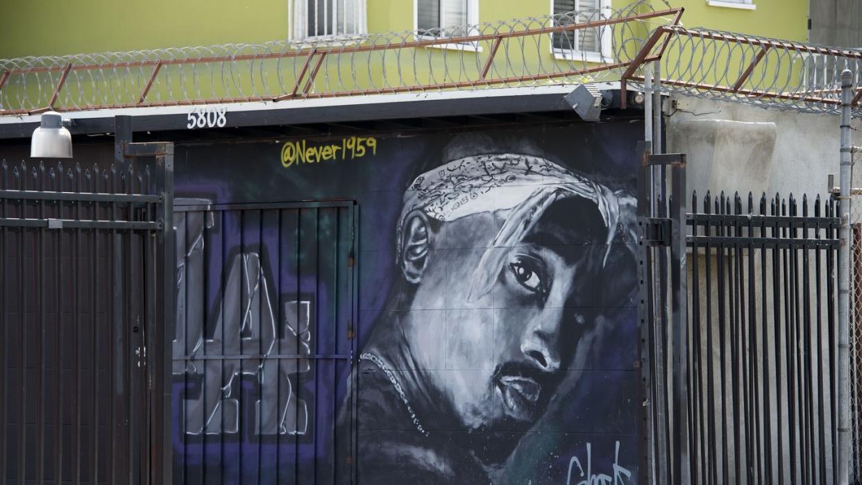 mural painting of tupac shakur in black and white on a purple and black background