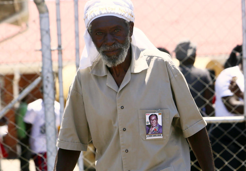 A supporter of former Zimbabwean President Robert Mugabe is seen near the entrance to his rural home in Zvimba, about 100 kilometer north west of the capital Harare, Saturday, Sept. 28, 2019. According to a family spokesperson Mugabe is expected to be buried at the residence after weeks of drama mystery and contention over his burial place.(AP Photo/Tsvangirayi Mukwazhi)