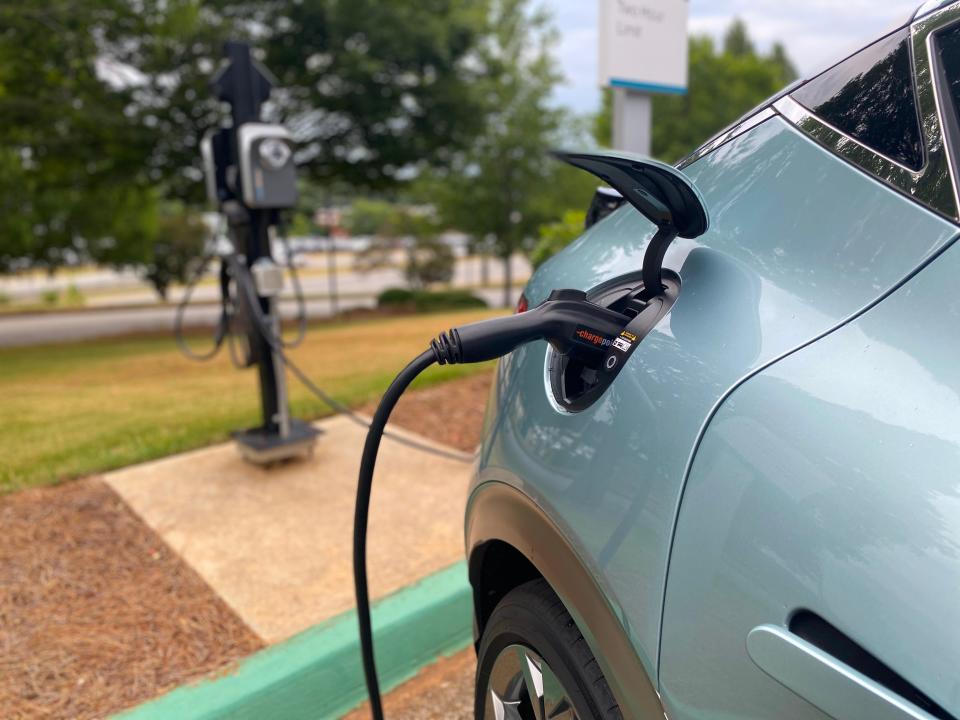 A green Genesis GV60 plugged into a charger.