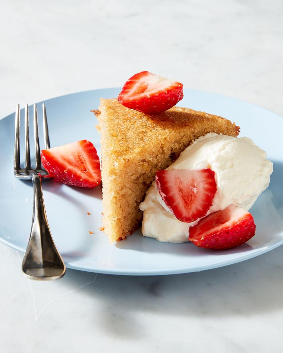 slice of almond cake on a blue plate with strawberries and whipped cream