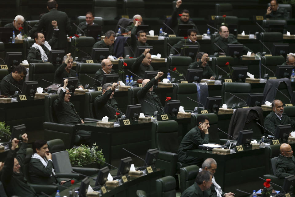 Wearing the uniform of the Iranian Revolutionary Guard, lawmakers chant slogan during an open session of parliament in Tehran, Iran, Tuesday, April 9, 2019. Chanting "Death to America," Iranian lawmakers convened an open session of parliament Tuesday following the White House's decision to designate Iran's elite paramilitary Revolutionary Guard a foreign terrorist organization. (AP Photo/Hamidreza Rahel/ICANA)