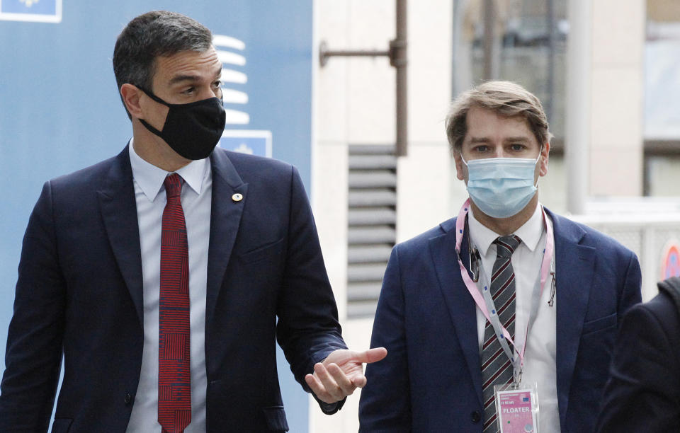 Spain's Prime Minister Pedro Sanchez, left, speaks with a member of his delegation as he arrives for an EU summit at the European Council building in Brussels, Sunday, July 19, 2020. Leaders from 27 European Union nations meet face-to-face for a third day to assess an overall budget and recovery package spread over seven years estimated at some 1.75 trillion to 1.85 trillion euros. (Francois Walschaerts, Pool Photo via AP)