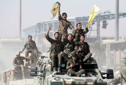 Syrian Democratic Forces (SDF) fighters ride atop military vehicles as they celebrate victory in Raqqa, Syria, October 17, 2017. REUTERS/Erik De Castro