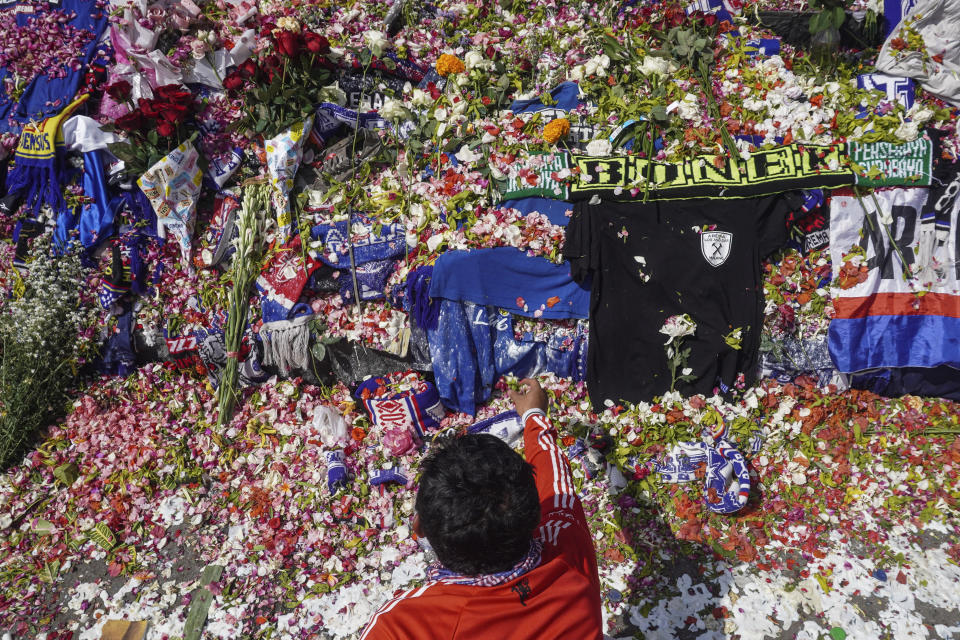 A man throws flowers outside Kanjuruhan Stadium where a soccer stampede killed more than 100 people on Saturday, in Malang, East Java, Indonesia, Tuesday, Oct. 4, 2022. An Indonesian police chief and nine elite officers were removed from their posts Monday and 18 others were being investigated for responsibility in the firing of tear gas inside a soccer stadium that set off a stampede, officials said. (AP Photo/Dicky Bisinglasi)