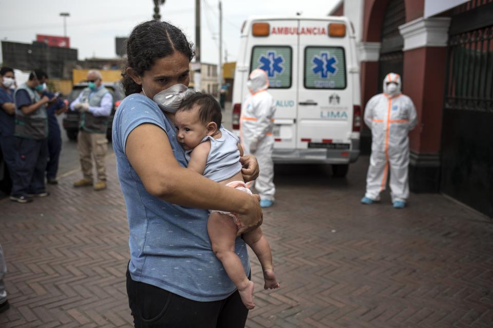 La venezolana María de Los Ángeles Mendez sostiene a su hija de tres meses, María, mientras espera para aplicar para refugio en la Plaza de Toros de Acho en Lima, Perú, el martes 31 de marzo de 2020. (AP Foto/Rodrigo Abd)