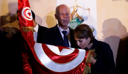 Tunisian presidential candidate Kais Saied and his wife Ichraf Chebil react after exit poll results were announced in a second round runoff of the presidential election in Tunis