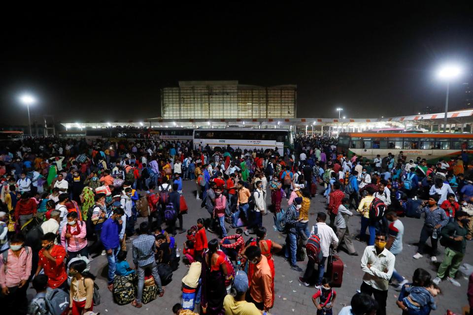 <p>Migrant workers gather at a bus station to board buses to return to their villages after Delhi government ordered a six-day lockdown to limit the spread of the coronavirus disease in Ghaziabad on the outskirts of New Delhi, India on 19 April</p> (Reuters)