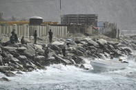 Security forces guard the shore area and a boat in which authorities claim a group of armed men landed in the port city of La Guaira, Venezuela, Sunday, May 3, 2020. Interior Minister Nestor Reverol said on state television that security forces overcame before dawn Sunday an armed maritime incursion with speedboats from neighboring Colombia in which several attackers were killed and others detained. (AP Photo/Matias Delacroix)