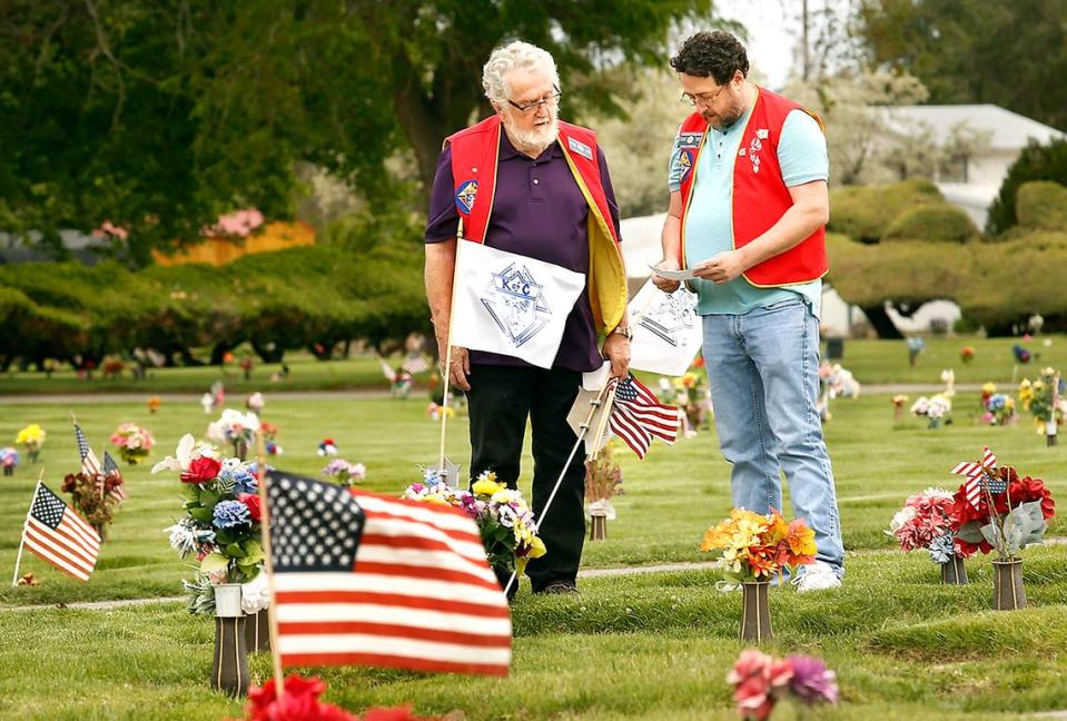 2020 FILE PHOTO — Pat McCabe, left, and his son, Andrew, with Knights of Columbus at the Parish of the Holy Spirit Catholic Church in Kennewick, refer to a list of names while placing flags on graves at Desert Lawn Memorial Park.