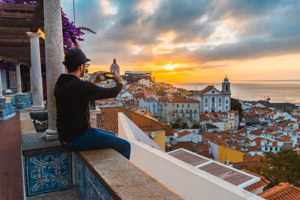 A tourist photographs the sunrise in Lisbon, Portugal, ranked as the top city in the world for remote workers.