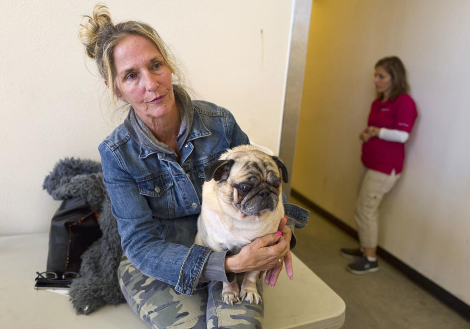 <p>Evacuee Tracey Moechel sits with her dog Muggsy outside of an evacuation center set up at the Taft Charter High School gymnasium in Woodland Hills, section of Los Angeles on Nov. 9, 2018. Moechel said Friday the center wouldn’t allow her dog to sleep inside. (Photo: Richard Vogel/AP) </p>