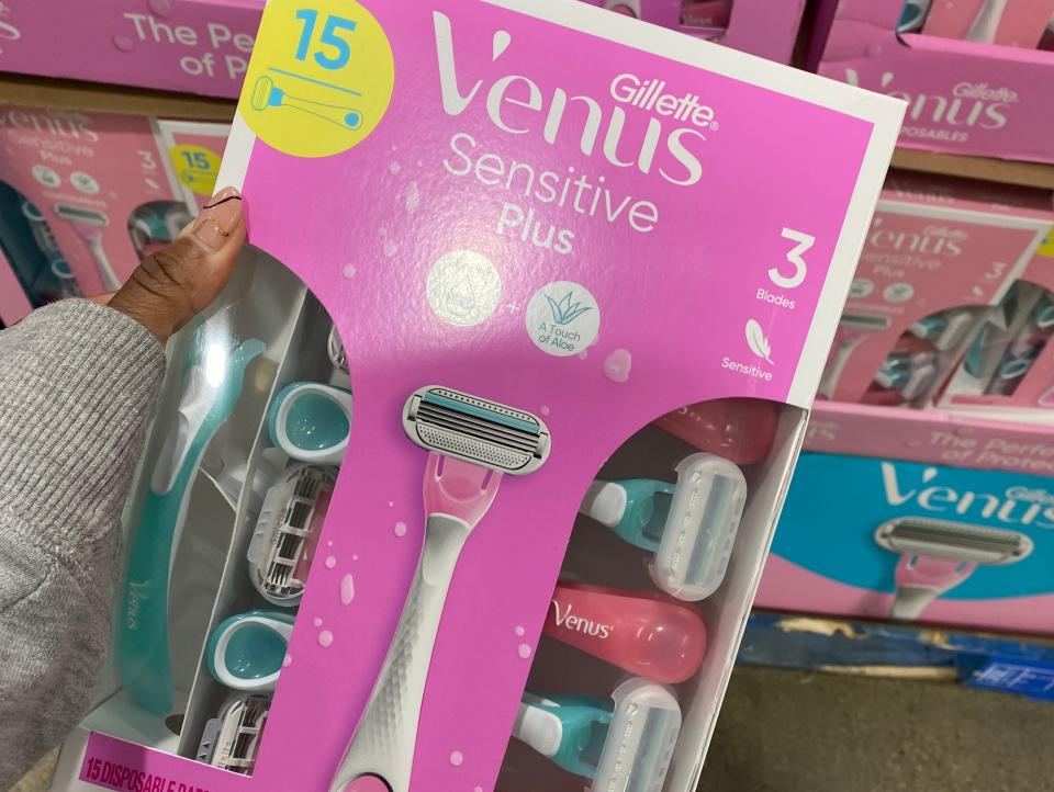 The writer holds a pink pack of pink and white Venus razors