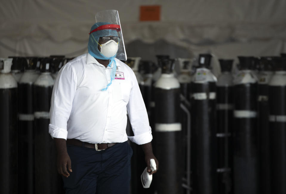 A health worker in a protective suit walks past oxygen cylinders at a makeshift emergency unit at Steve Biko Academic Hospital in Pretoria, South Africa, Monday, Jan. 11, 2021, which is battling an ever-increasing number of Covid-19 patients. (AP Photo/Themba Hadebe)