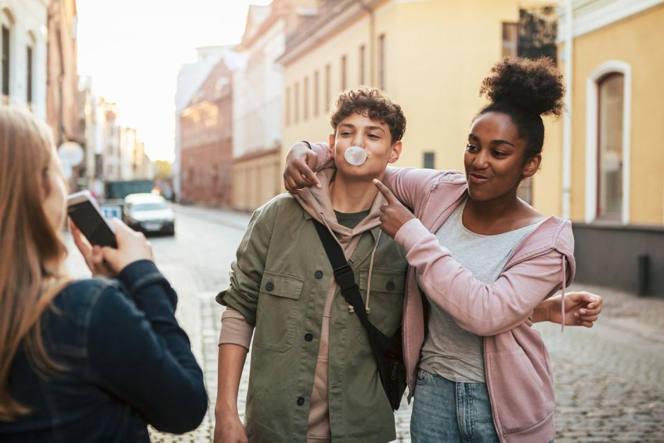 three teenagers friends having fun with taking photos on bubble gum