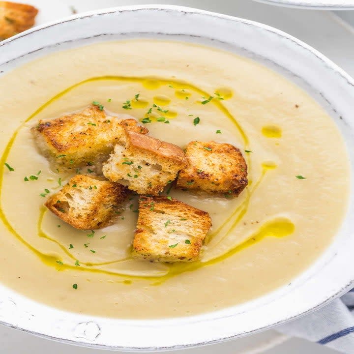 A bowl of creamy sunchoke soup with croutons.
