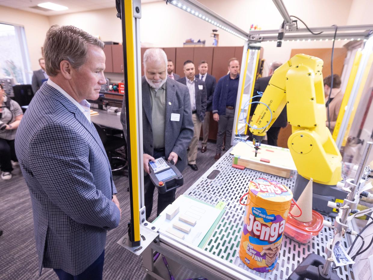 Lt. Gov. Jon Husted, left, looks on as Richard Hartmann, a professor of electrical/electronic engineering technology, demonstrates a robotic arm during a Friday tour of the AI facilities at Stark State College before an AI roundtable.