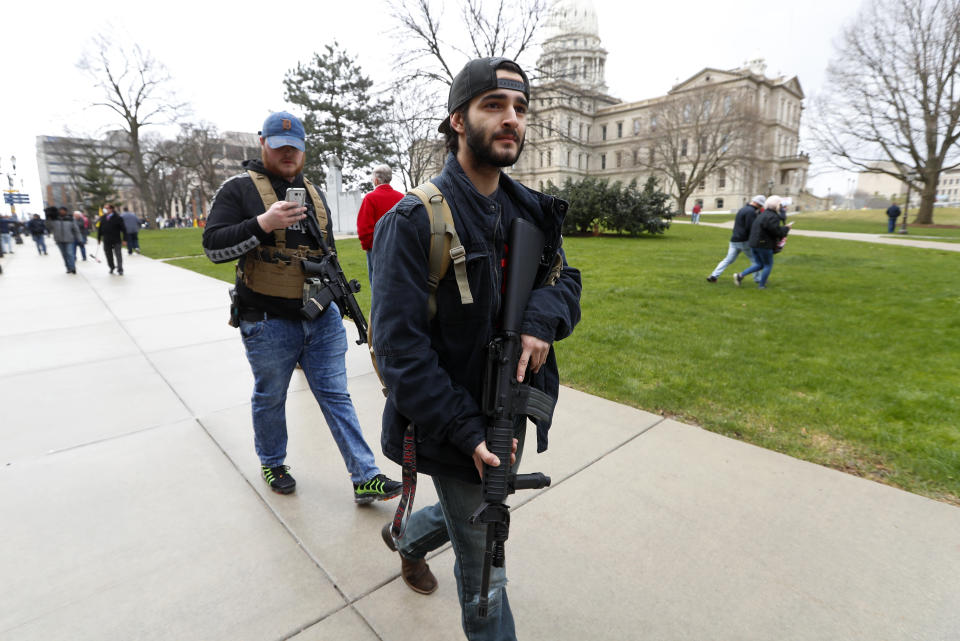 In this April 15, 2020 photo, protesters carry guns outside the Capitol Building in Lansing, Mich. Michigan Attorney General Dana Nessel said Friday, May 8, 2020, that a commission overseeing the state Capitol can legally ban guns from the building, contradicting panel leaders' contention that only the Legislature can do so. (AP Photo/Paul Sancya)