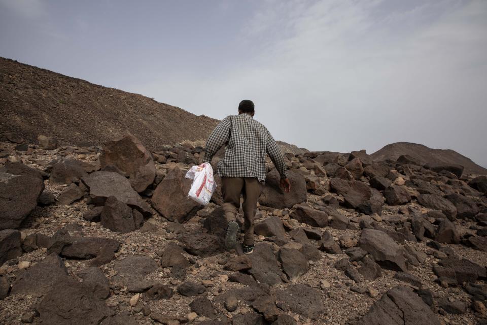 In this July 14, 2019 photo, 35-year-old Mohammed Eissa, an Ethiopian farmer, walks on the side of a highway, near Lac Assal, Djibouti. People here say they belong to migrants who like Eissa embarked on an epic journey of hundreds of miles, from villages and towns in Ethiopia and Somalia, through the Horn of Africa country of Djibouti, then across the sea and through the war-torn country of Yemen. (AP Photo/Nariman El-Mofty)