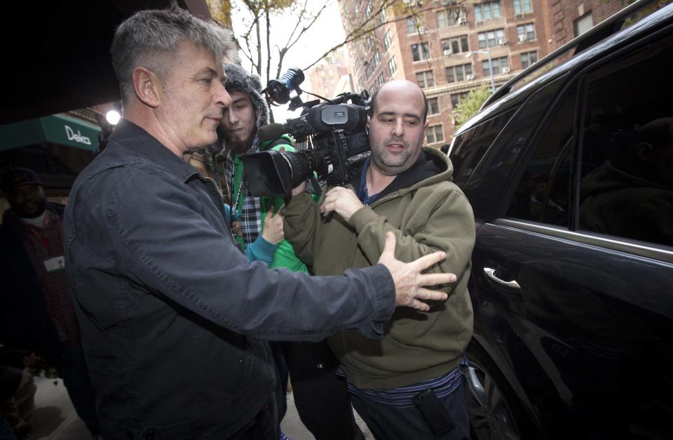 Actor Alec Baldwin directs a TV photographer out of his way in front of his apartment building in New York