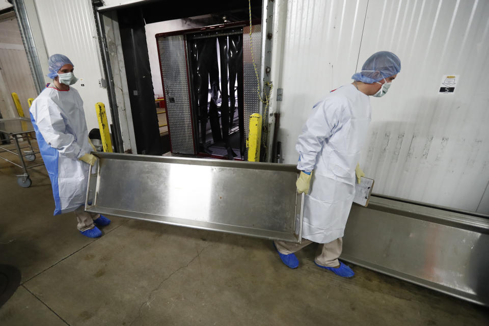 In this Tuesday, May 5, 2020, photo, Illinois National Guard members return a body tray to be sanitized on the loading dock at the Cook County Medical Examiner's auxiliary surge storage center after an emergency-management truck arrived with half-a-dozen bodies in Chicago. Incoming bodies to the surge center, with a capacity to hold 2,000 bodies, are taken to one of three rooms with the combined square footage of a football field. (AP Photo/Charles Rex Arbogast)