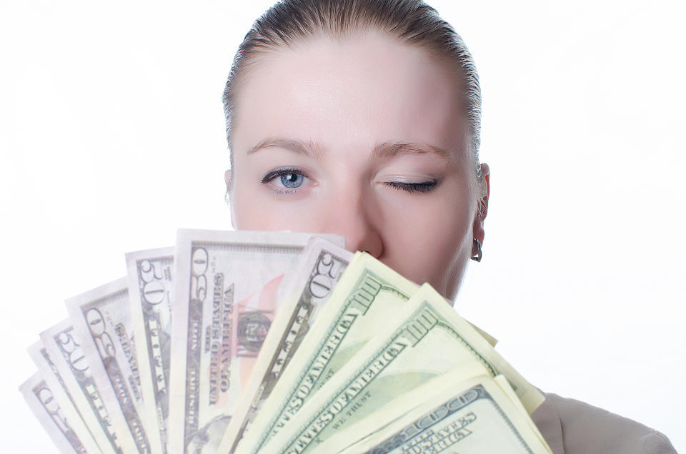 Young woman holding a lot of cash and winking