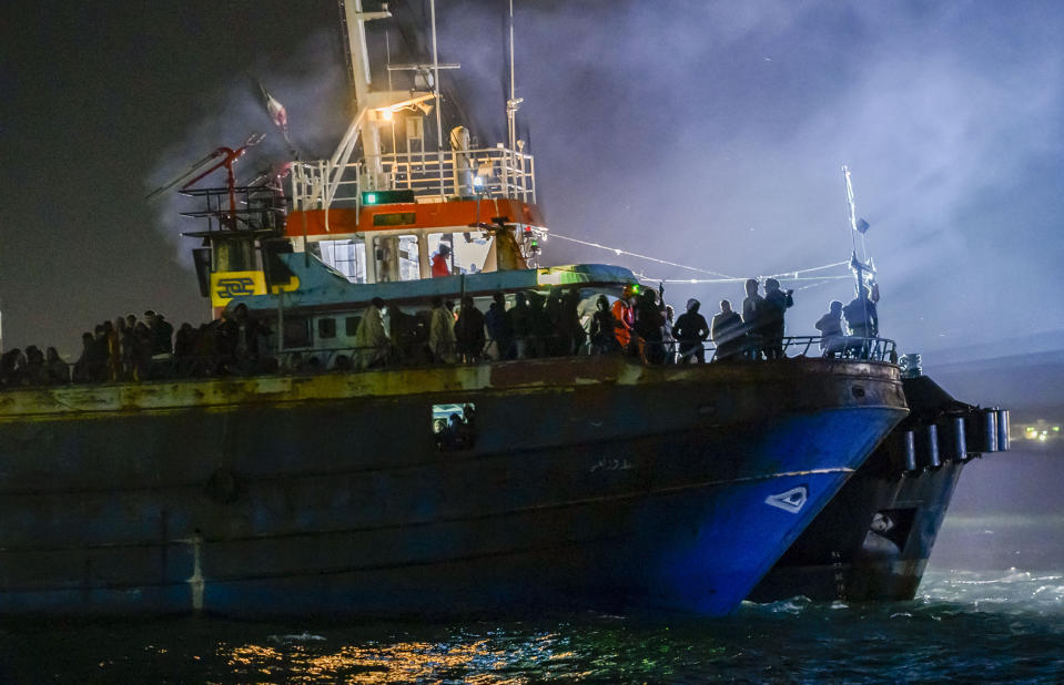 A fishing boat with some 500 migrants enters the southern Italian port of Crotone, early Saturday, March 11, 2023. The Italian coast guard was responding to three smugglers boats carrying more than 1,300 migrants “in danger” off Italy’s southern coast, officials said Friday. Three small coast guard boats were rescuing a boat with 500 migrants about 700 miles off the Calabria region, which forms the toe of the Italian boot. (AP Photo/Valeria Ferraro)