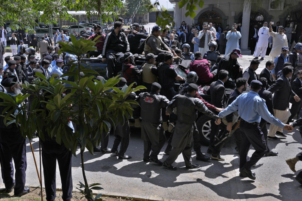 Security personnel escort a vehicle of former Prime Minister Imran Khan as he arrives for his court appearance, in Islamabad, Pakistan, Monday, March 27, 2023. A Pakistani court ruled in defense of former Prime Minister Khan, granting him protection from arrest as lawsuits mounted against the ousted premier, with police charging him with incitement to violence in several cases when his followers clashed with the security forces this month. (AP Photo/Anjum Naveed)