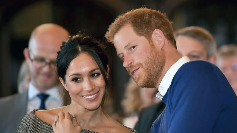 In this Thursday Jan. 18, 2018 file photo, Britain’s Prince Harry talks to Meghan Markle as they watch a dance performance by Jukebox Collective in the banqueting hall during a visit to Cardiff Castle, Wales. None of the royal family attended the christening of Prince Harry’s daughter.