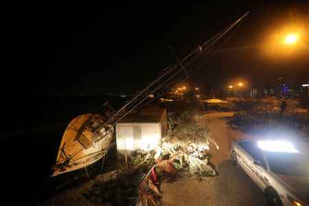 A police car is seen by a damaged boat in the darkness as many areas of Miami still without electricity after Hurricane Irma strikes Florida, in Miami, Florida, September 11, 2017. REUTERS/Carlos Barria