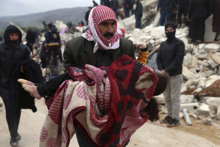 EDS NOTE: GRAPHIC CONTENT - A man carries the body of an earthquake victim in the Besnia village near the Turkish border, Idlib province, Syria, Monday, Feb. 6, 2023. A powerful earthquake has caused significant damage in southeast Turkey and Syria and many casualties are feared. Damage was reported across several Turkish provinces, and rescue teams were being sent from around the country. (AP Photo/Ghaith Alsayed)