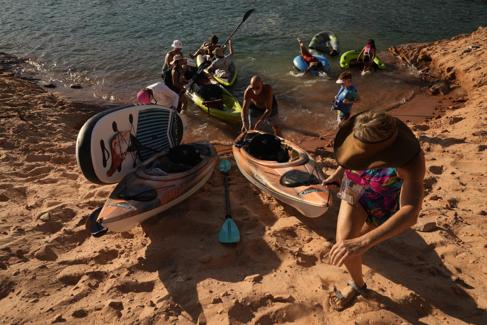 FILE - Tourists carry a kayak up a sandy hill Tuesday, June 7, 2022, in Page, Ariz. As Lake Powell levels drop, recreation is becoming tougher to access as boat ramps and marinas close. (AP Photo/Brittany Peterson, File)