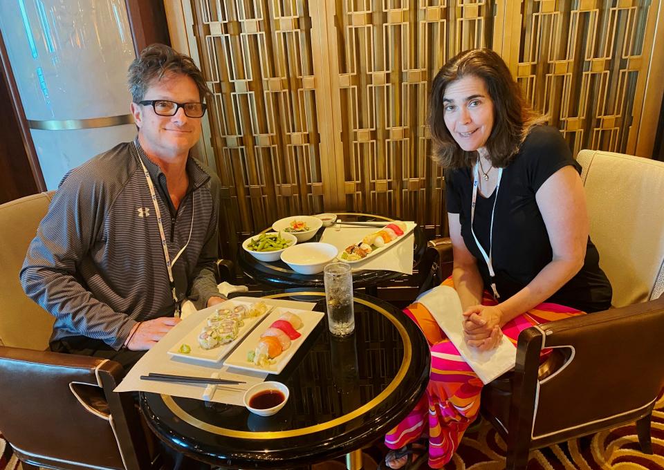 A man and woman take a picture while eating sushi.