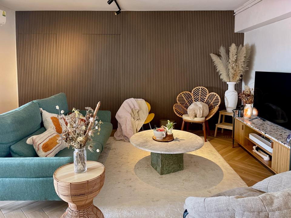 A view of the living room with wooden fluted panels in the back that hide two doors, which lead to the bedrooms.