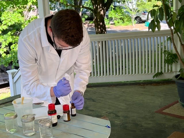 a person in a white lab coat bends over test tube samples