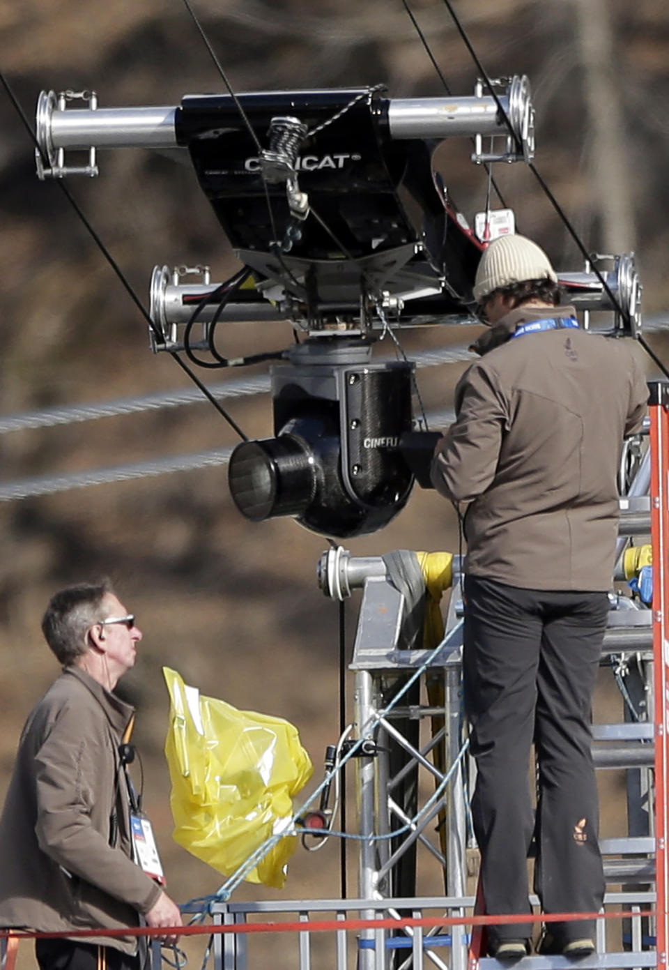 Technicians prepare a spider camera prior to a nordic combined training session in the ski jumping stadium at the 2014 Winter Olympics, Monday, Feb. 10, 2014, in Krasnaya Polyana, Russia. (AP Photo/Matthias Schrader)