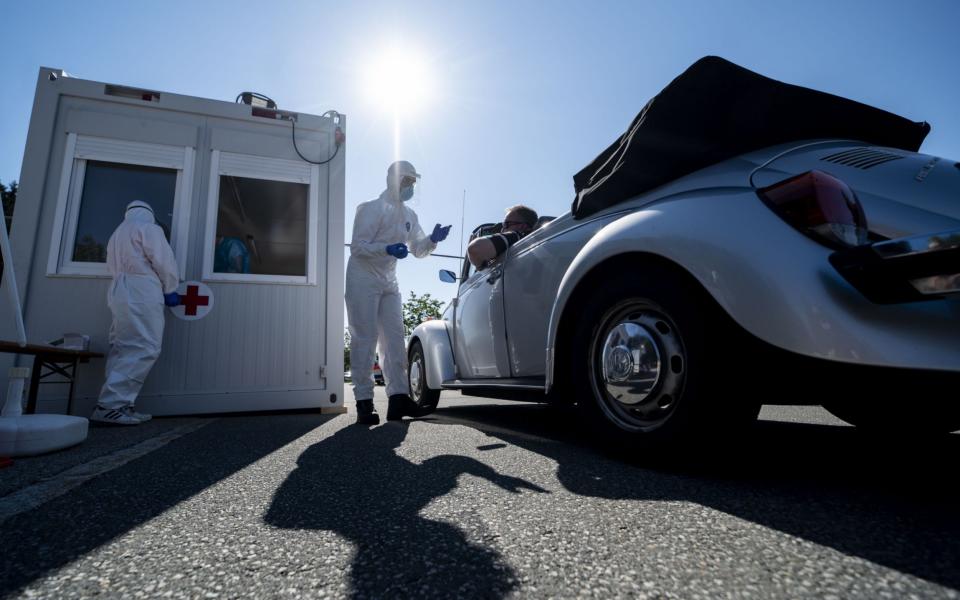 Mandatory Credit: Photo by LUKAS BARTH-TUTTAS/EPA-EFE/Shutterstock (10727582c) A volunteer from the Bavarian Red Cross is testing a traveler at a coronavirus test station at the service area Hochfelln-Nord on the A8 motorway between Salzburg and Munich near Bergen, Bavaria, Germany, 30 July 2020. Travelers entering Bavaria now have the opportunity to be tested for the COVID-19 coronavirus voluntarily and free of charge at airports, motorways and railway stations. Testing for coronavirus at motorway near German-Austrian border, Bergen, Germany - 30 Jul 2020 - LUKAS BARTH-TUTTAS/EPA-EFE/Shutterstock