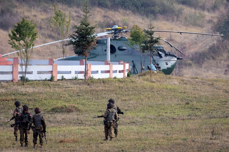 Soldiers approach a Myanmar military helicopter that had an accident while taking off from Lwe Khan