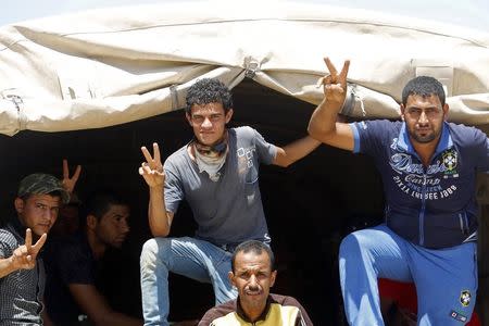 Shi'ite volunteers, who have joined the Iraqi army to fight against militants of the Islamic State, formerly known as the Islamic State of Iraq and the Levant (ISIL), gesture to the camera from inside a truck in Baghdad, July 9, 2014. REUTERS/Ahmed Saad