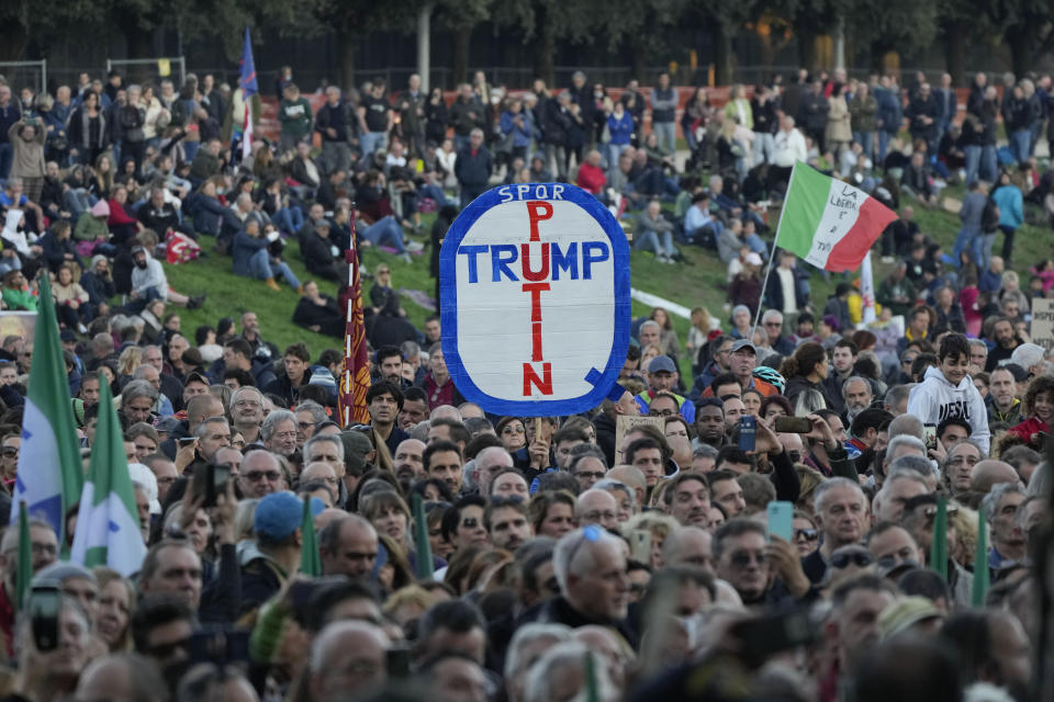 A demonstrator holds a banner reading "Putin, Trump" during a protest against restrictions for the unvaccinated in Rome Circus Maximus, Saturday, Nov. 20, 2021. With infections spiking again despite nearly two years of restrictions, the health crisis increasingly is pitting citizen against citizen — the vaccinated against the unvaccinated. (AP Photo/Alessandra Tarantino)